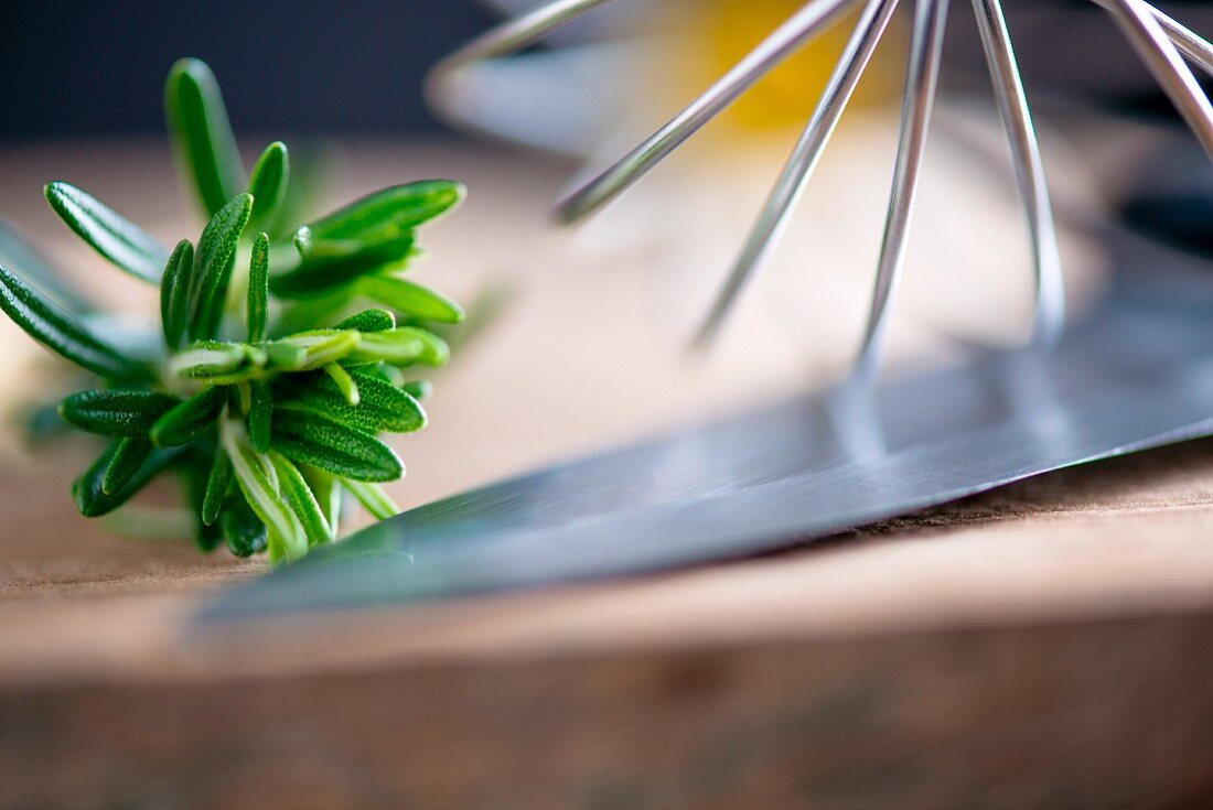 Rosemary, an egg whisk and a knife (close-up)