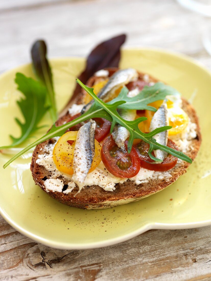 Bread topped with cream cheese, tomatoes and anchovies