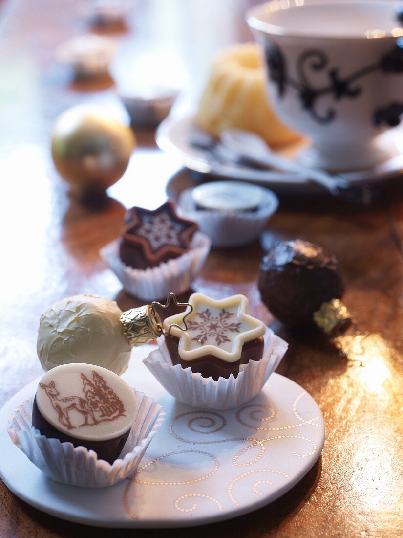 Verzierte Platte mit Schokoladenkonfekt in Papiermanschetten auf goldglänzender Unterlage