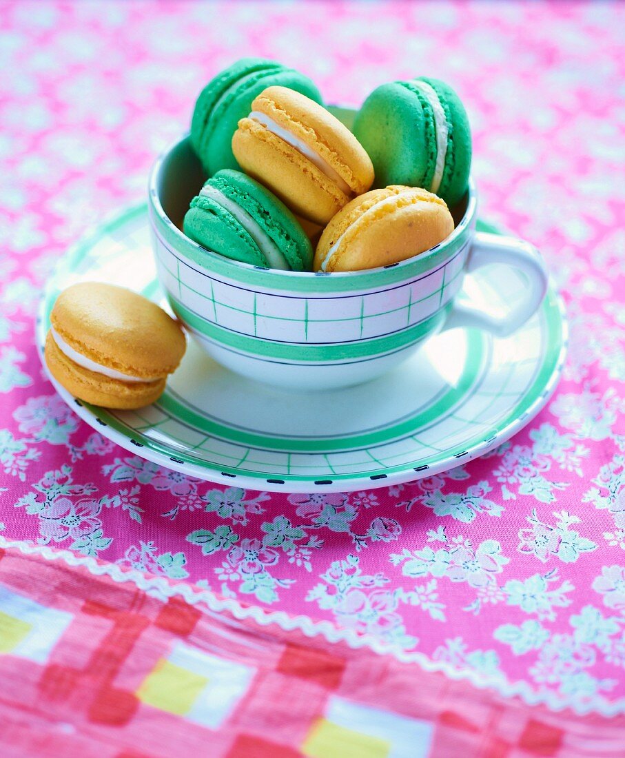 Green and yellow macaroons in a cup