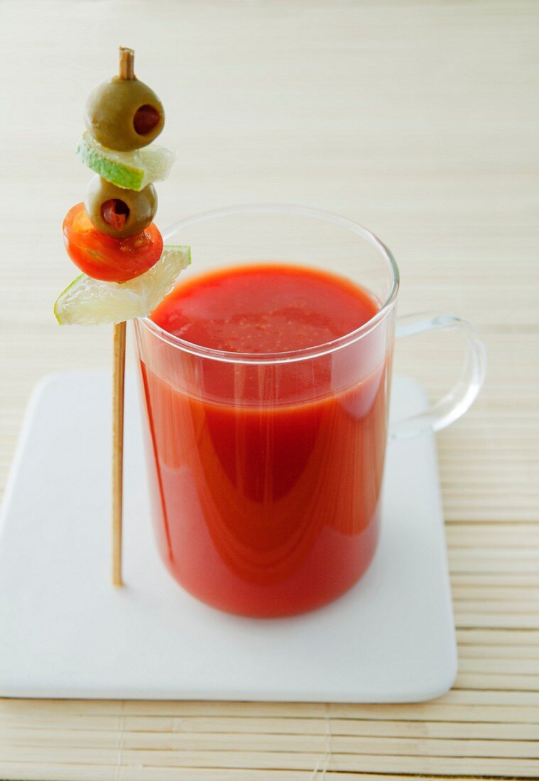 A glass of tomato juice with a vegetable skewer