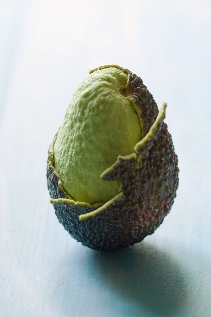 An avocado, partly peeled