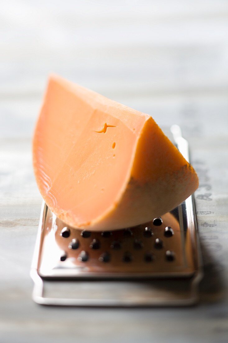 A wedge of Mimolette cheese on a cheese grater