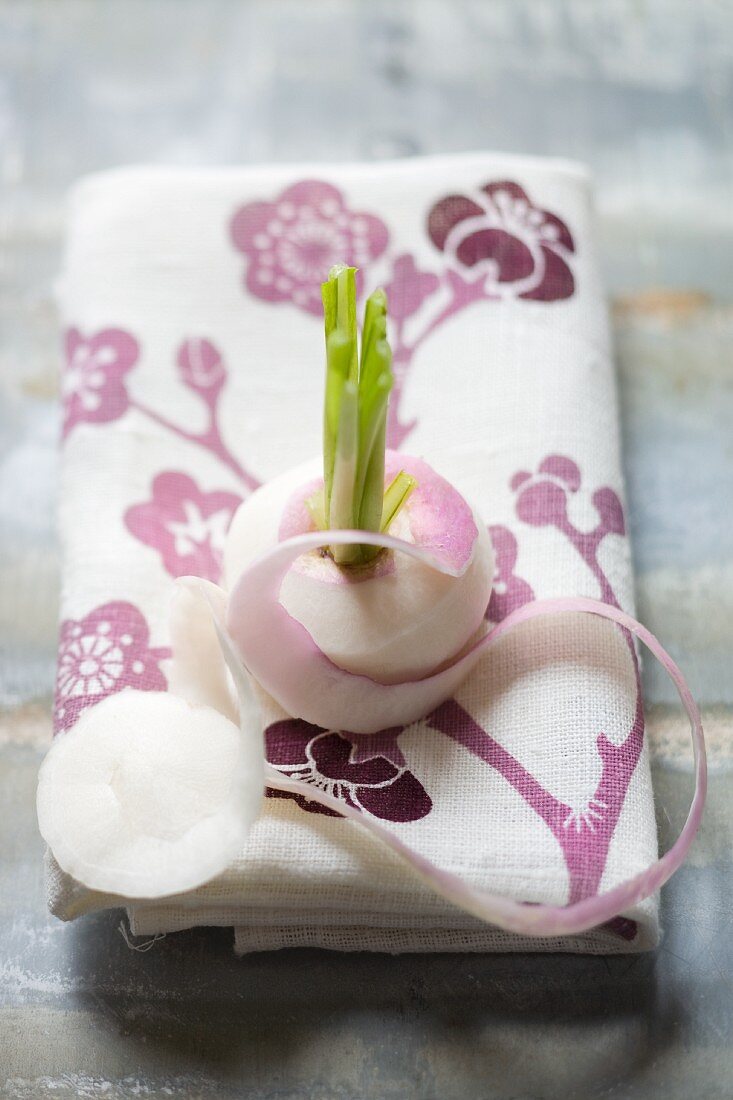 A peeled white turnip on a floral-patterned cloth