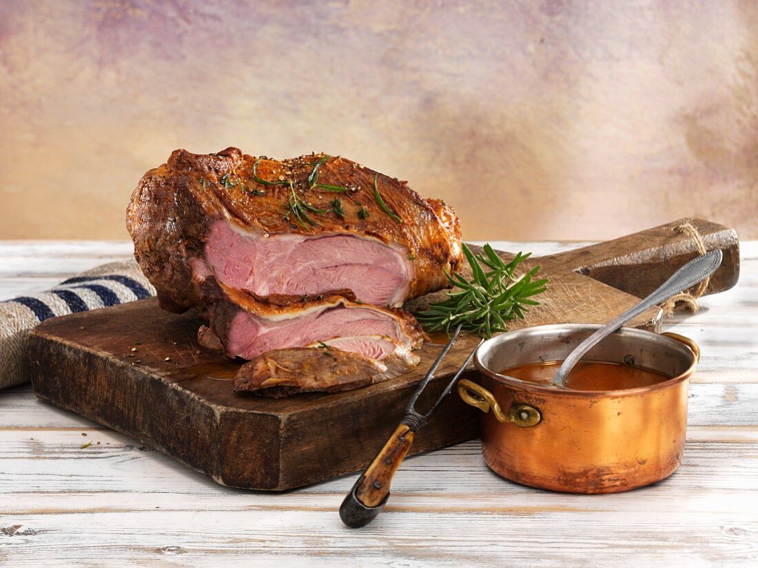 Leg of lamb, cooked pink, on a wooden board