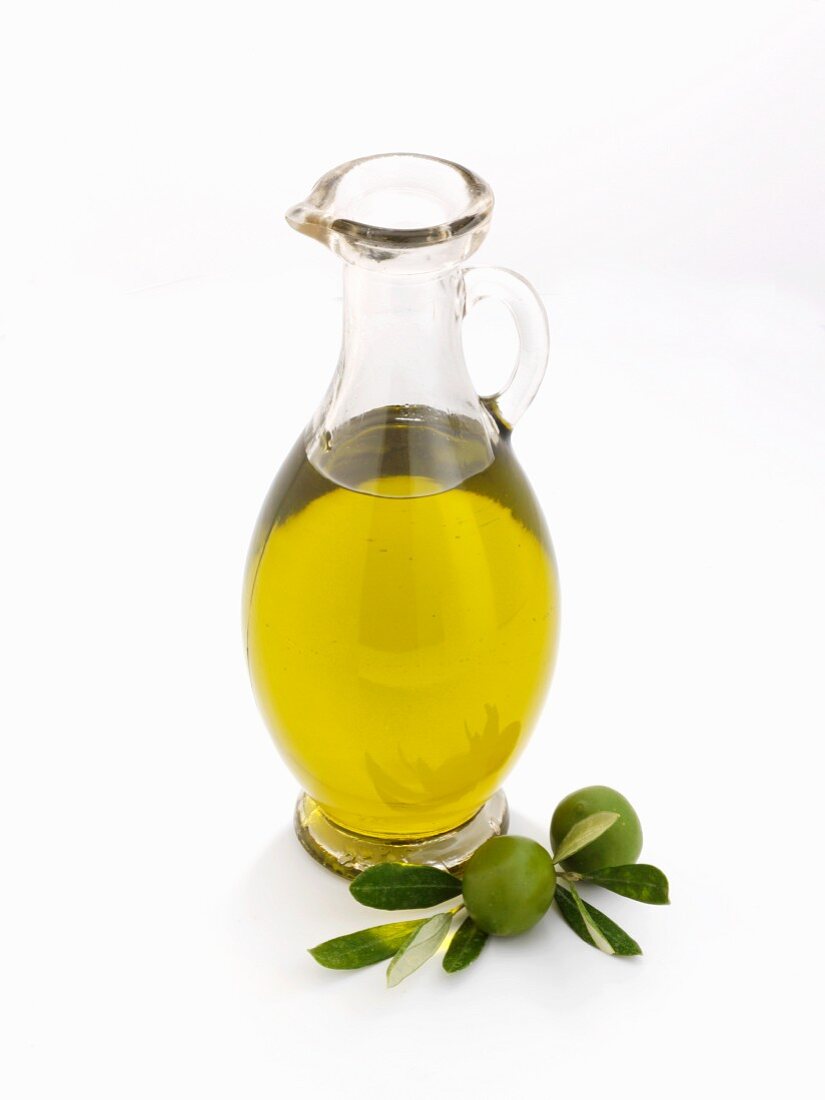 Glaskaraffe mit Olivenöl vor weißem Hintergrund
