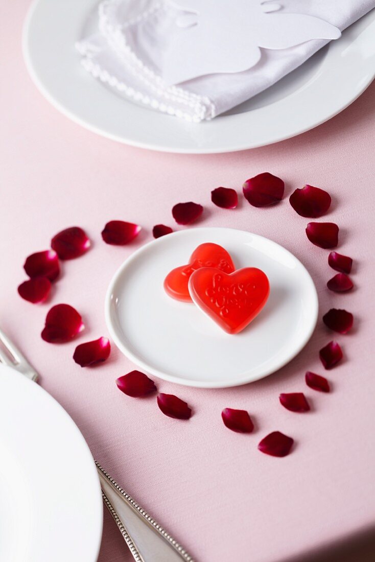 Rose petals arranged in shape of heart surrounding sweets on plate
