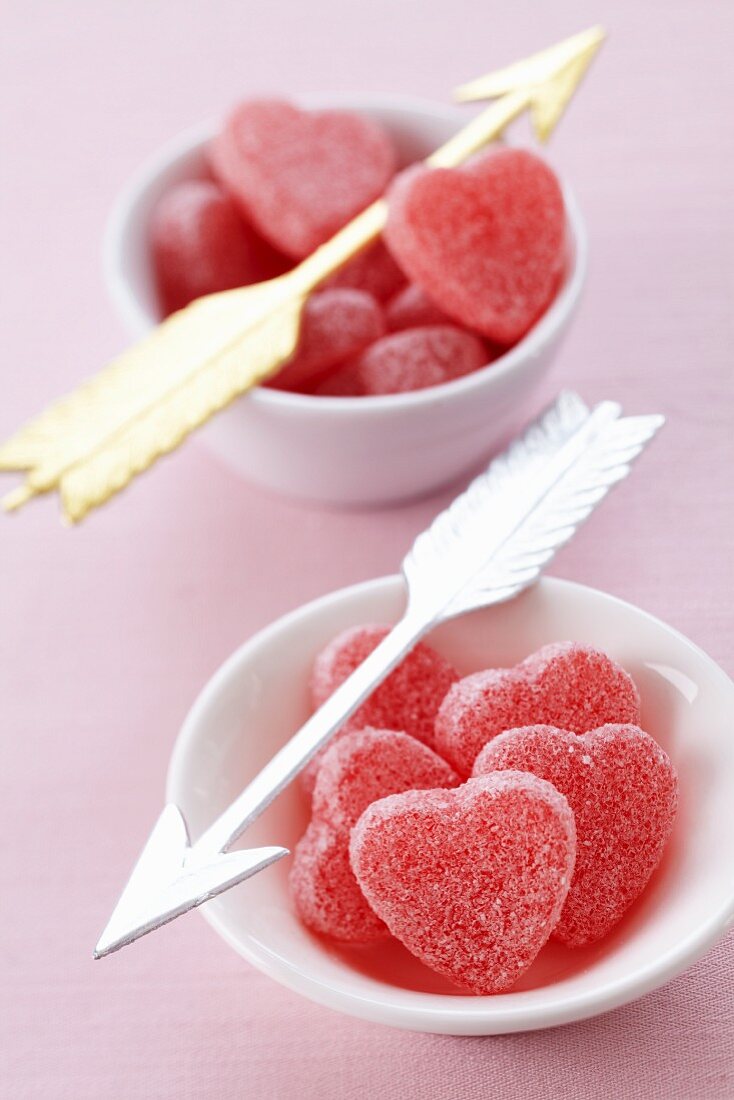 Heart-shaped bonbons in bowls with Cupid's arrows