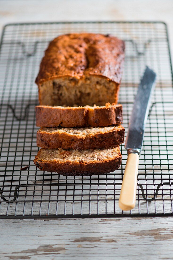 Banana and walnut bread, partly sliced, on a cooling rack