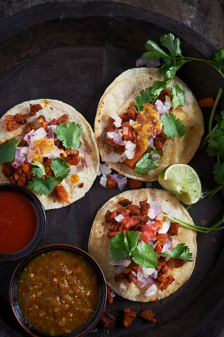 Drei Taco Al Pastor mit zwei Arten von Salsa