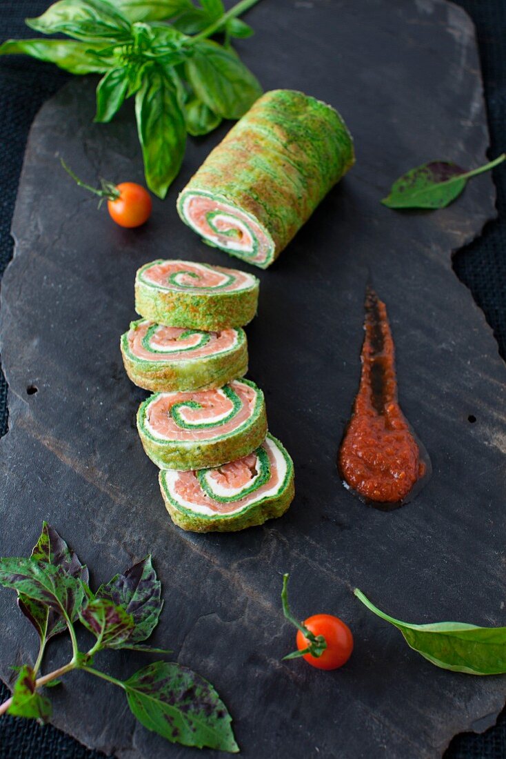 Spinach and Basil Smoked Salmon Roll; Sliced with Sauce on a Piece of Slate