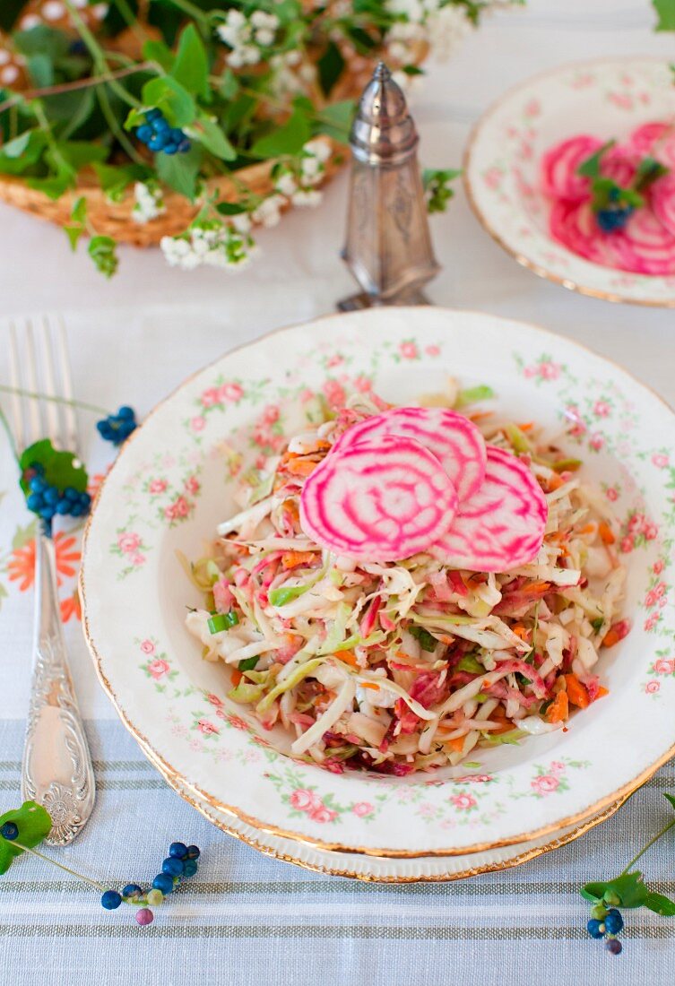 Cabbage Salad Topped with Sliced Variegated Beets; On a Table with a Basket of Flowers