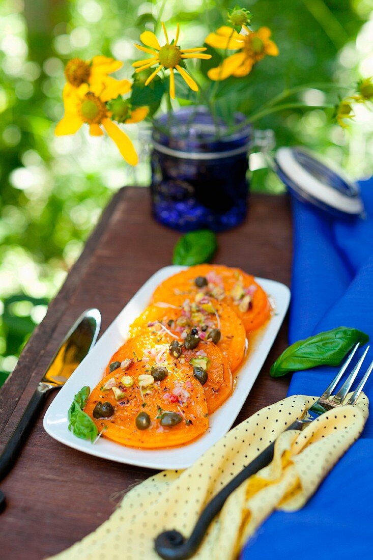 Pan Fried Yellow Tomatoes with Pistachio Caper Relish; On a Platter on an Outdoor Table