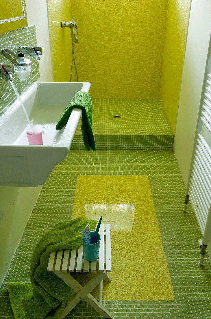 Narrow bathroom with green mosaic tiles and open shower area with lime green cladding