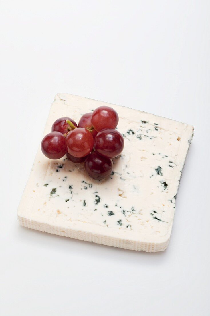 A slice of blue cheese and red grapes