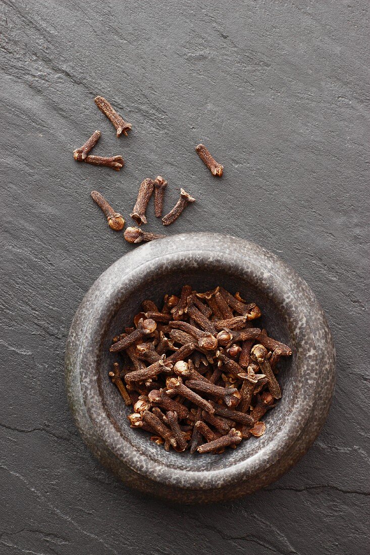 Cloves in a stone bowl on a slate slab