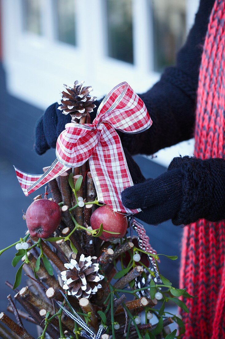 Decorating a Christmas tree made of twigs with a ribbon