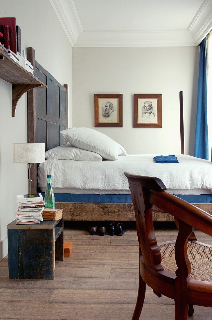 Rustic double bed with wooden headboard in bedroom with stucco frieze on ceiling