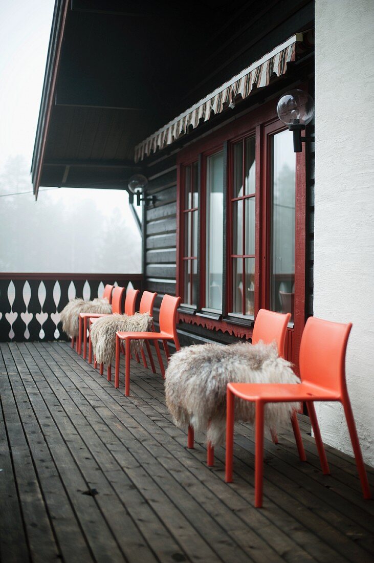 Sheepskins on red plastic chairs on wooden chalet balcony