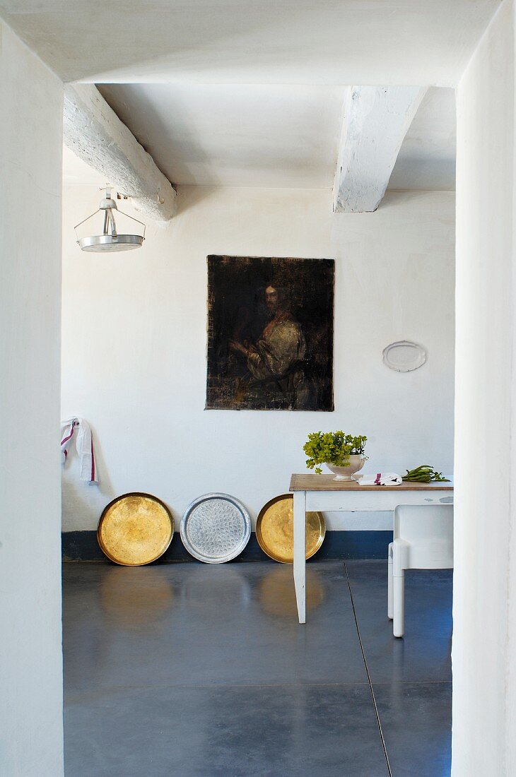 Gold and silver trays and Fresco-style picture on wall of spartan room with polished stone floor