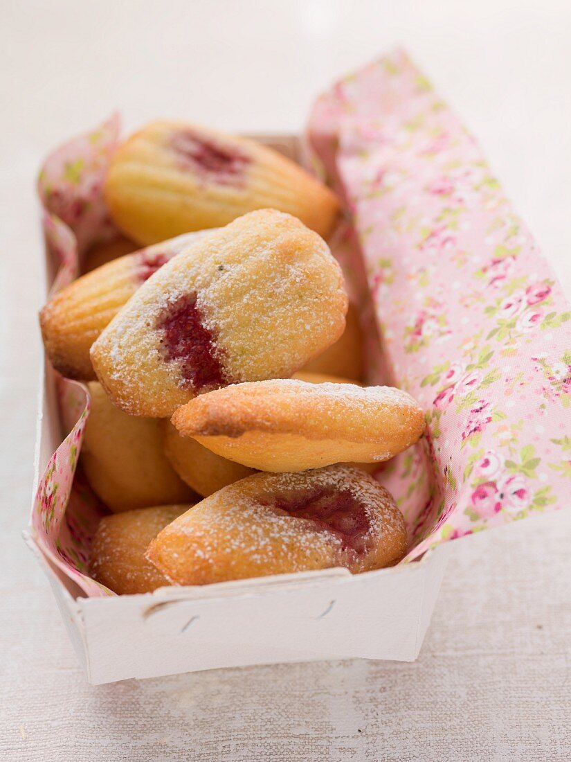 Madeleines mit Himbeermarmelade und Puderzucker in einer Schachtel