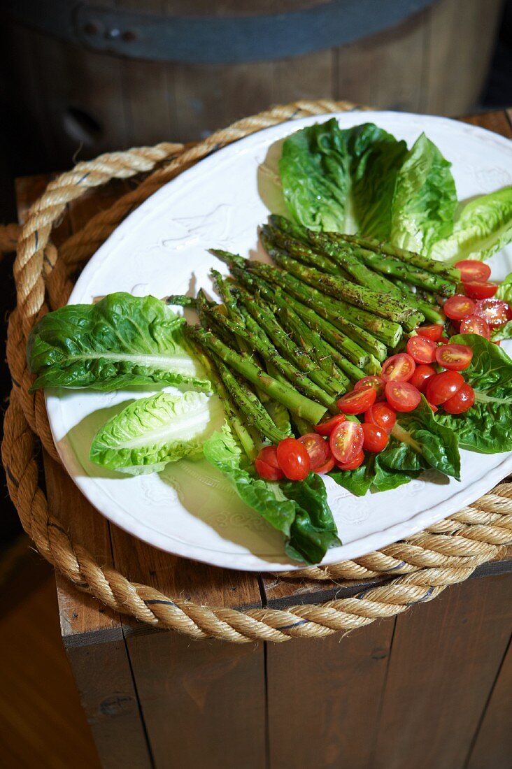 Grilled Asparagus Spears on a Platter with Marinated Cherry Tomatoes and Lettuce Leaves