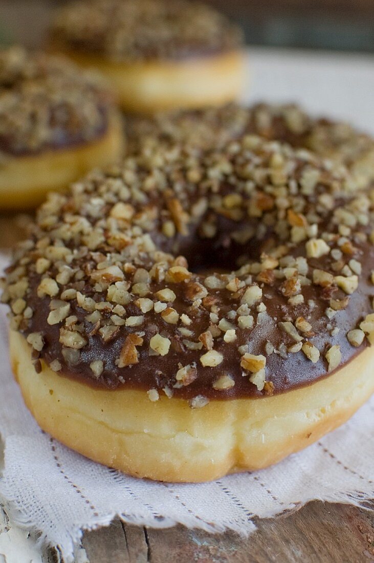 Doughnuts mit Schokoglasur und gehackten Nüssen (Close Up)