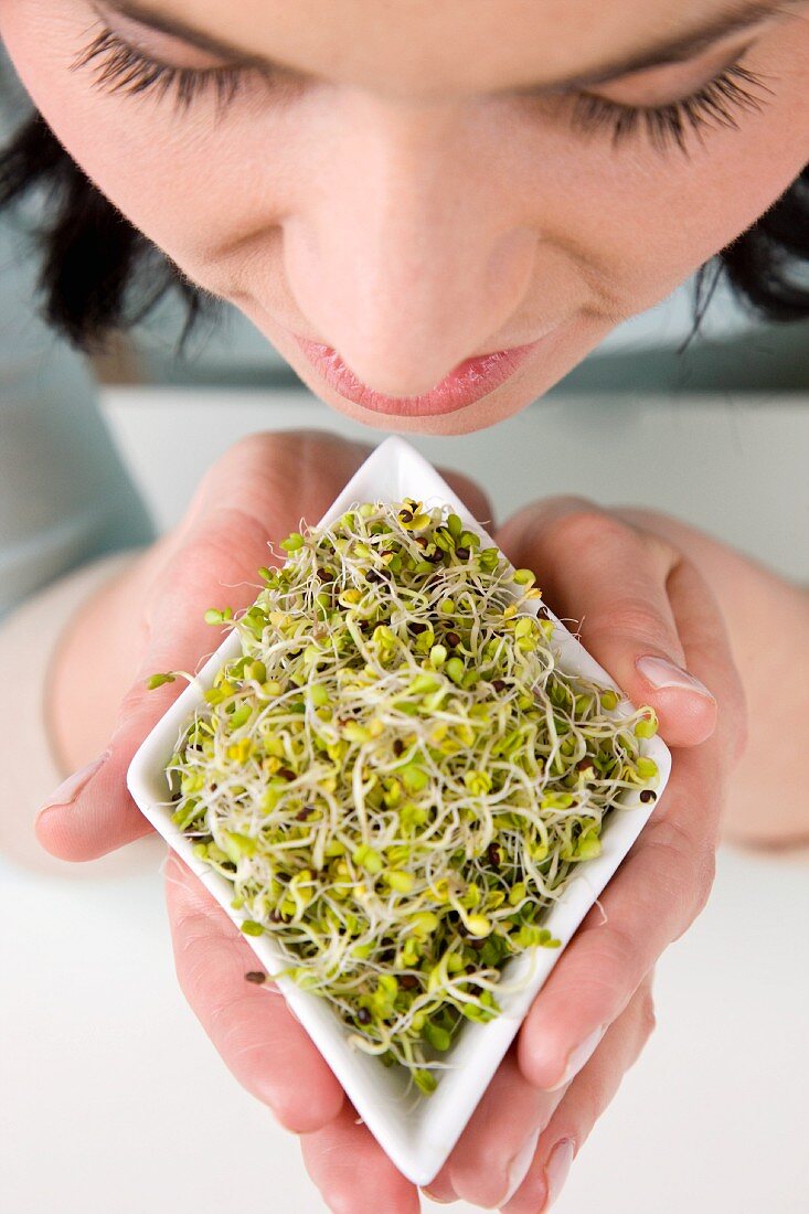 A woman holding a bowl of radish sprouts (view from above)