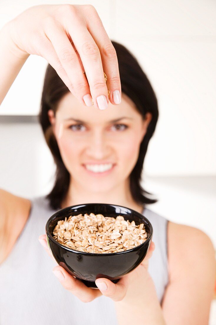 A woman holding up a bowl of porridge oats