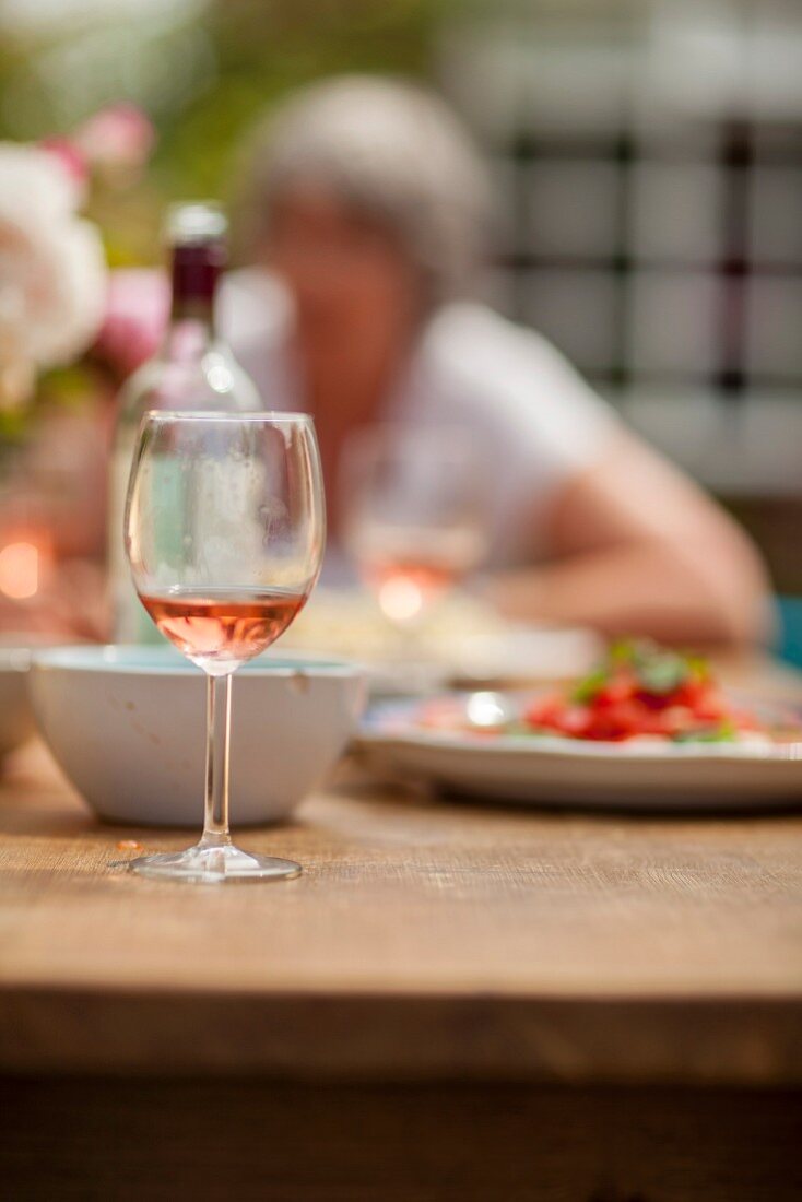 Ein Glas Rosewein auf einem Gartentisch