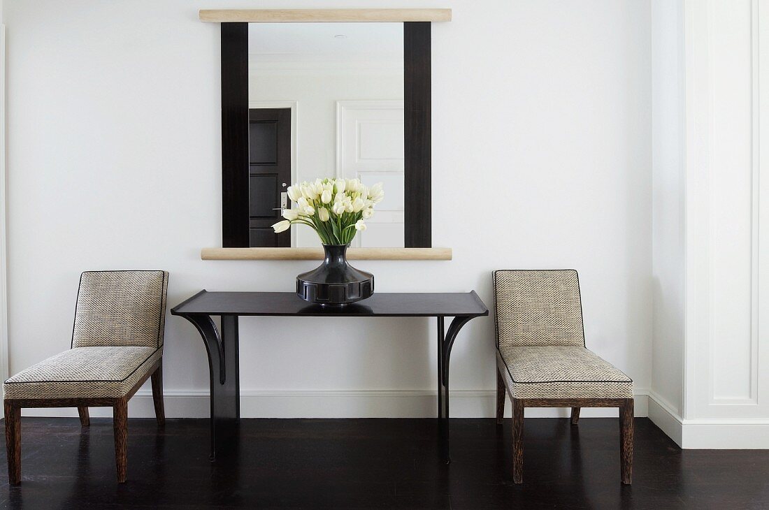 Upholstered chairs next to console table and mirror in classic setting