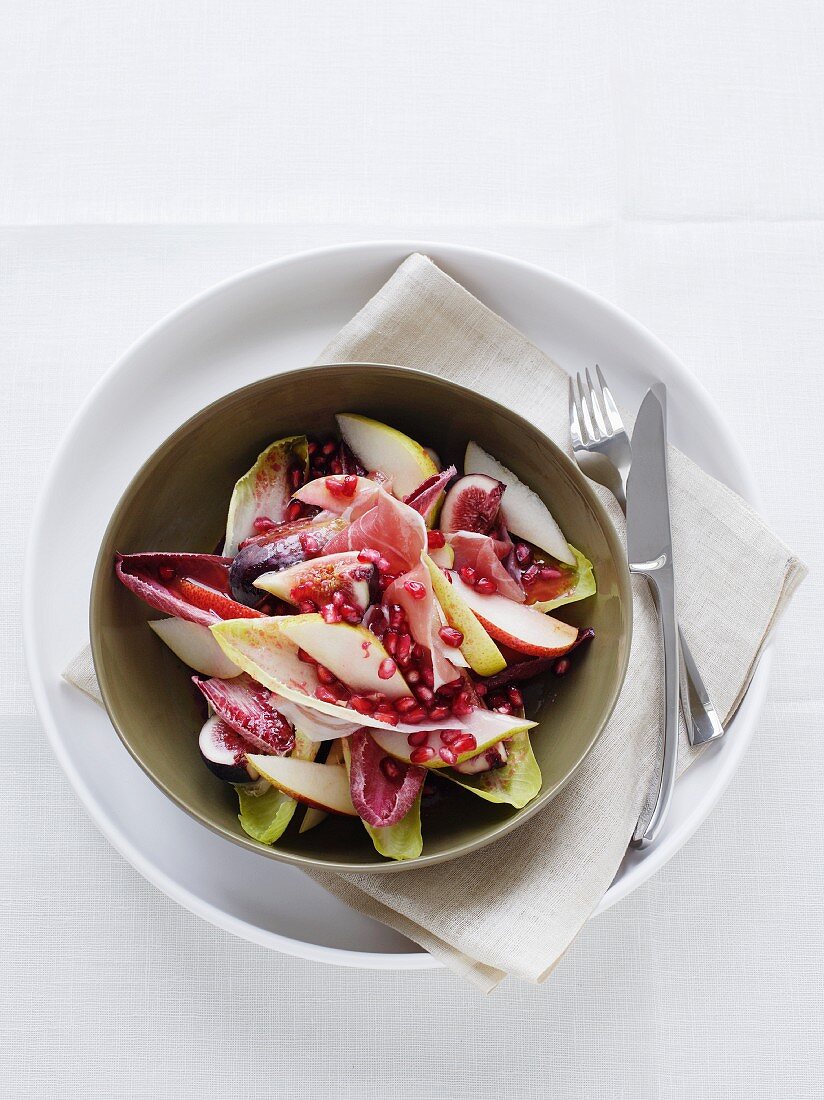 A salad of chicory with fruit and dry-cured ham