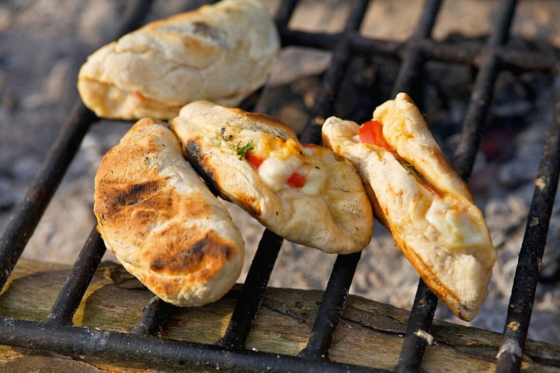 Small calzones on a grill rack over an open fire