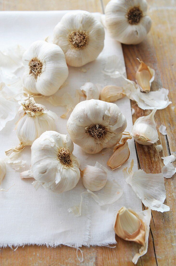 Garlic bulbs on a linen cloth and on a wooden surface