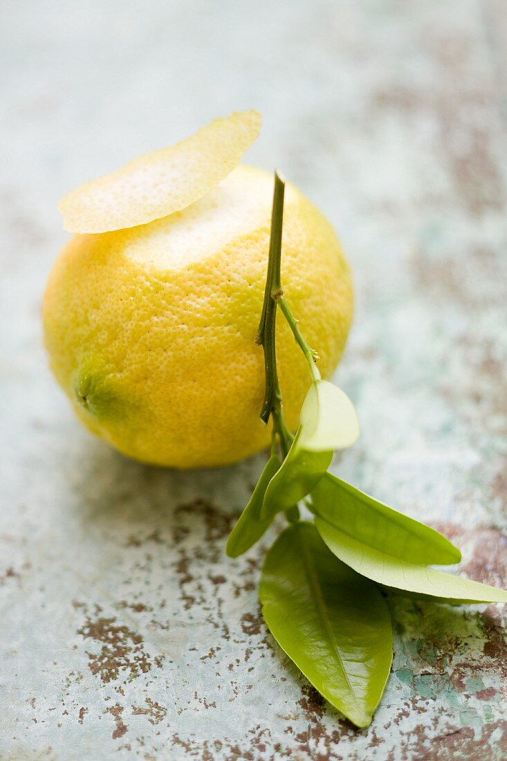 A lemon with a piece of peel and a twig