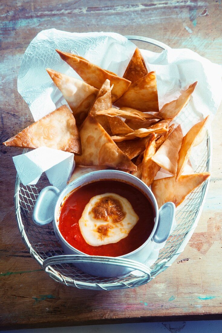 A tomato dip with cheese and tortilla chips