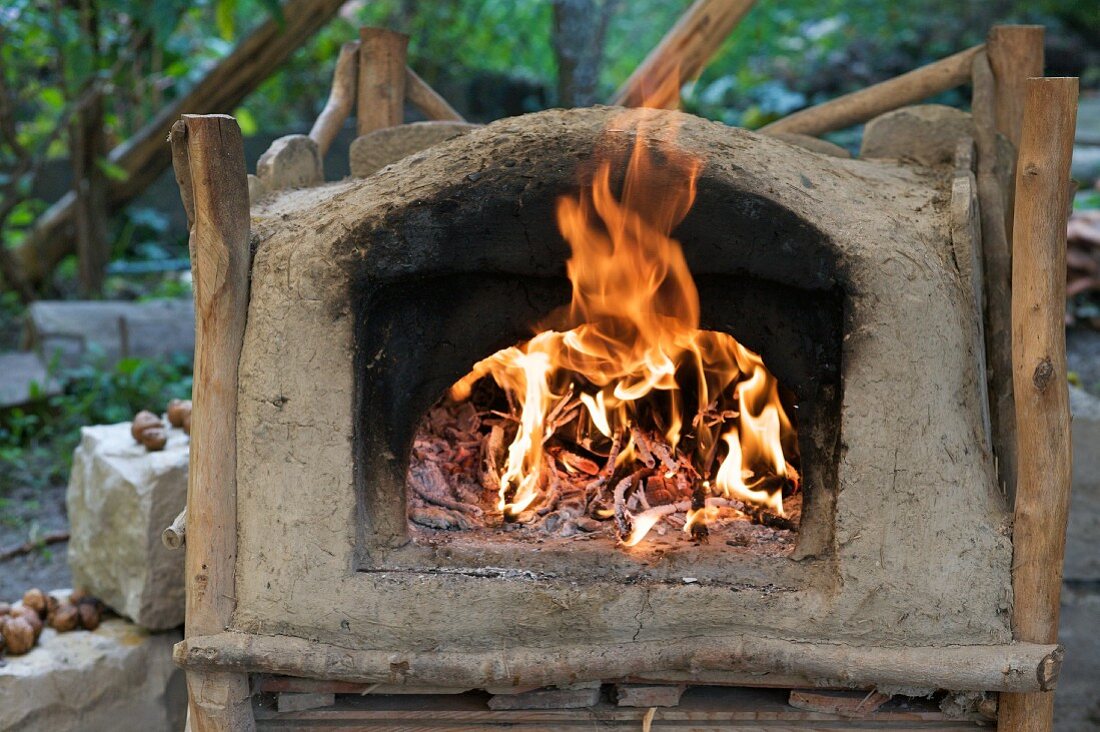 A clay oven with a fire burning inside
