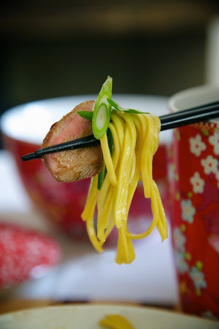 Chinese noodle salad with duck breast on chopsticks
