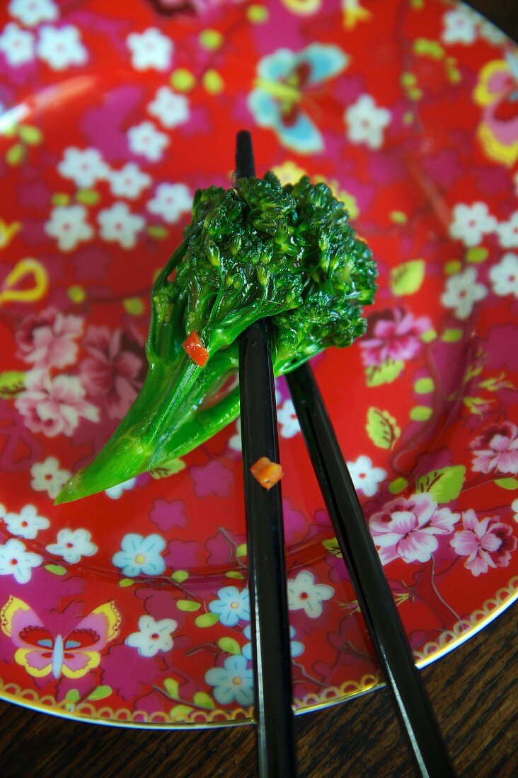 Broccoli with ginger and soy sauce on chopsticks