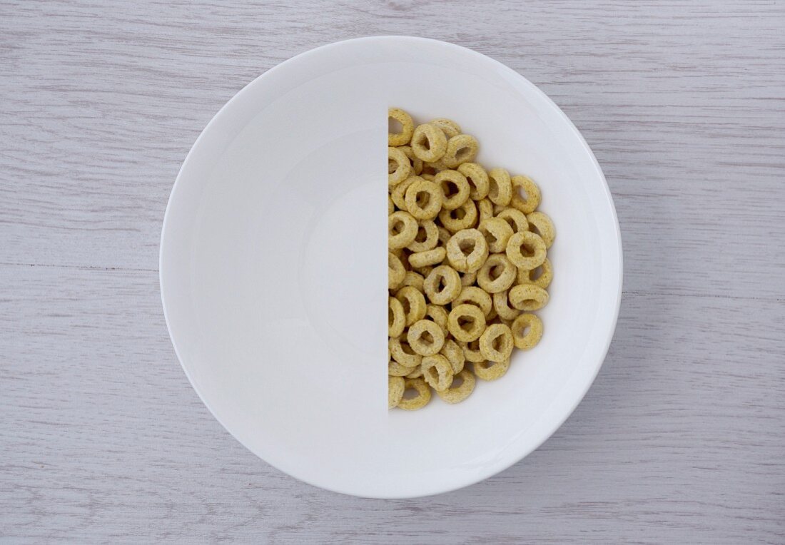 A halved portion of cereal hoops in a white bowl (view from above)
