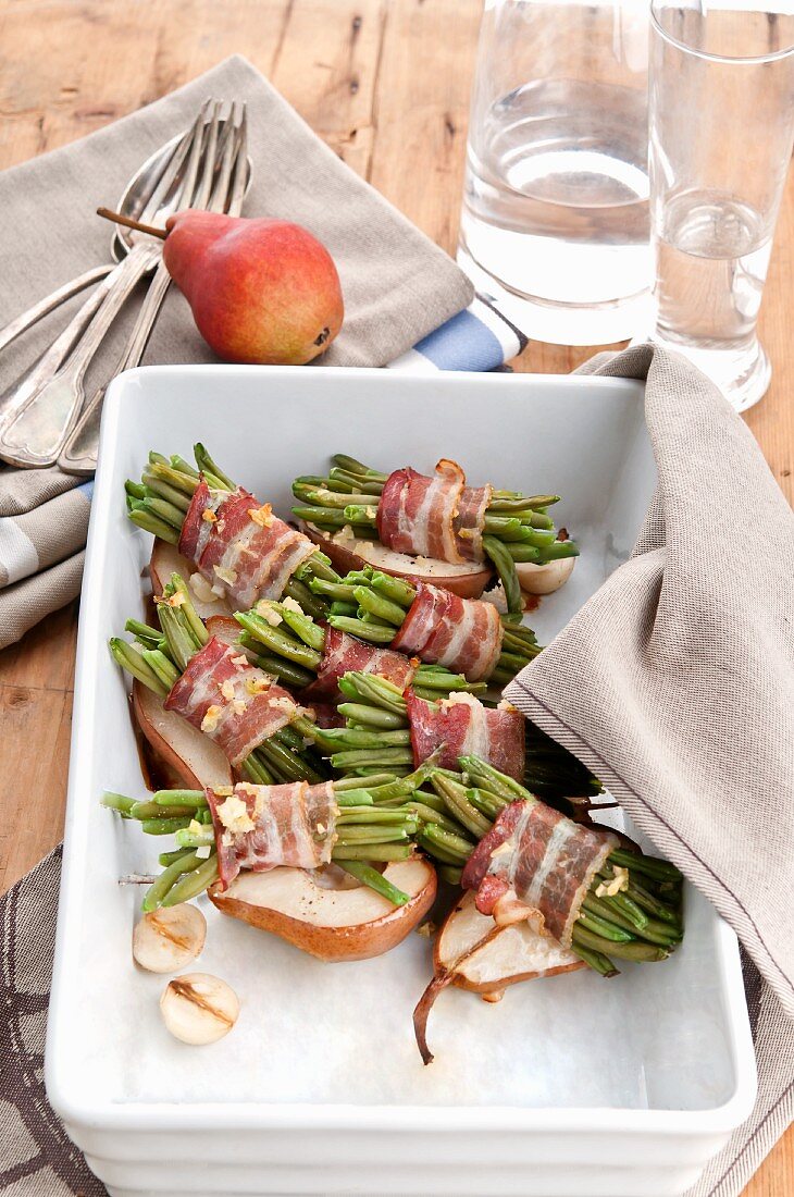 Roasted beans wrapped in bacon on top of baked pears