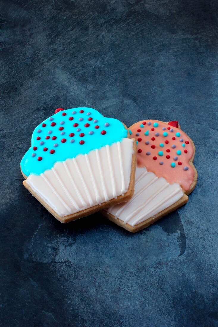 Two cupcake biscuits decorated in pink and pale blue