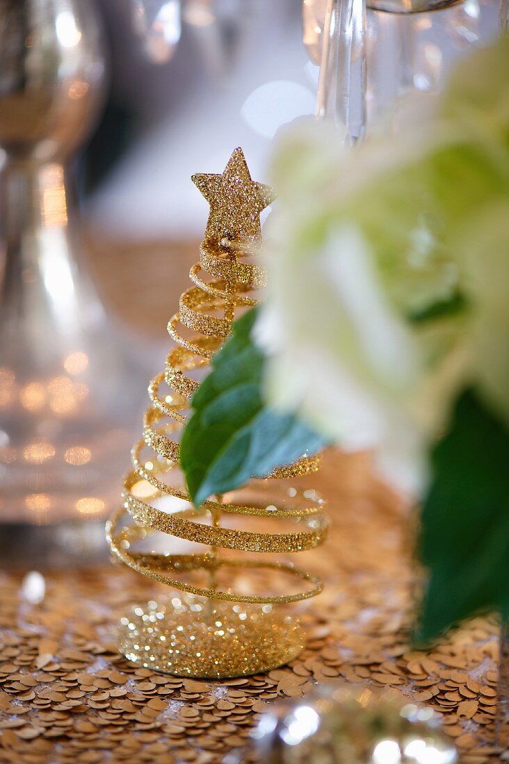 A golden glittering Christmas tree as table decoration