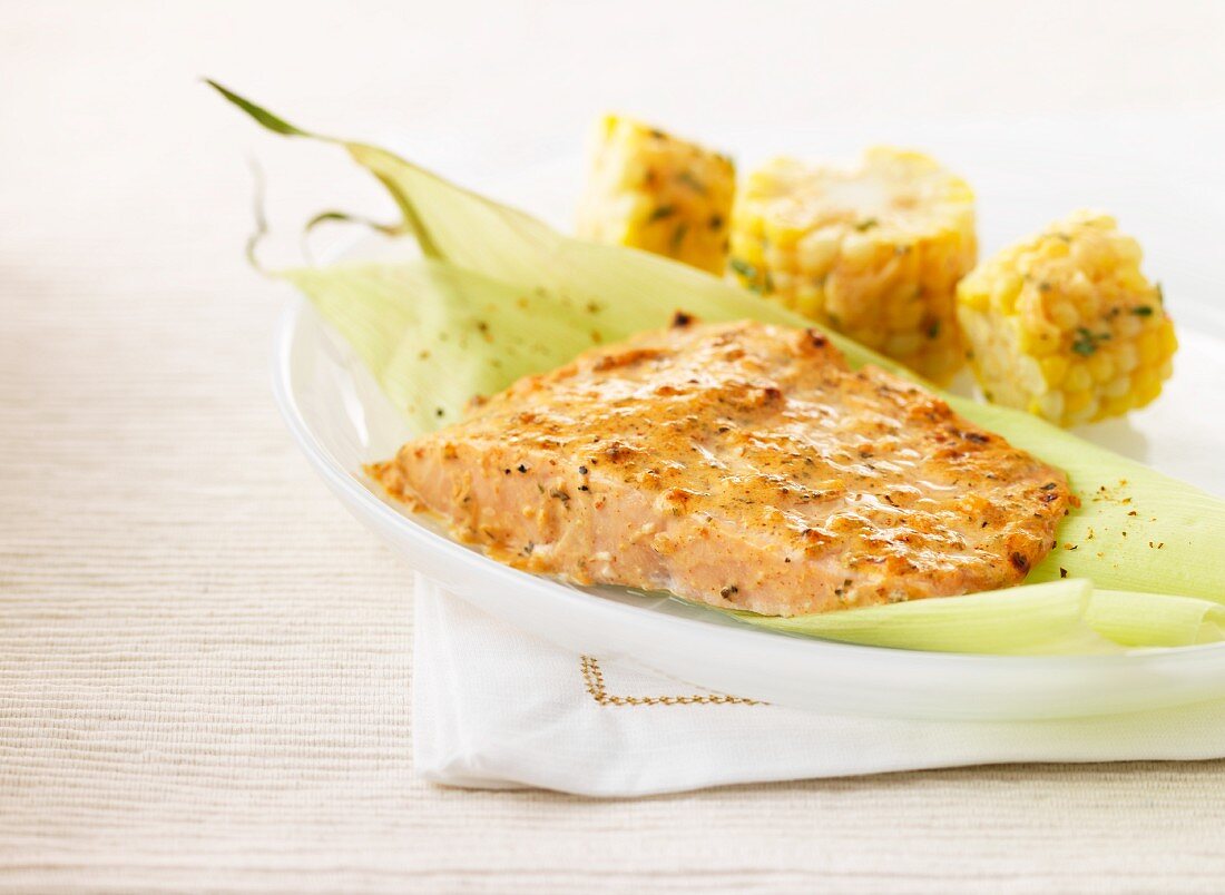 Salmon fillet on a corn leaf with chunks of corn on the cob