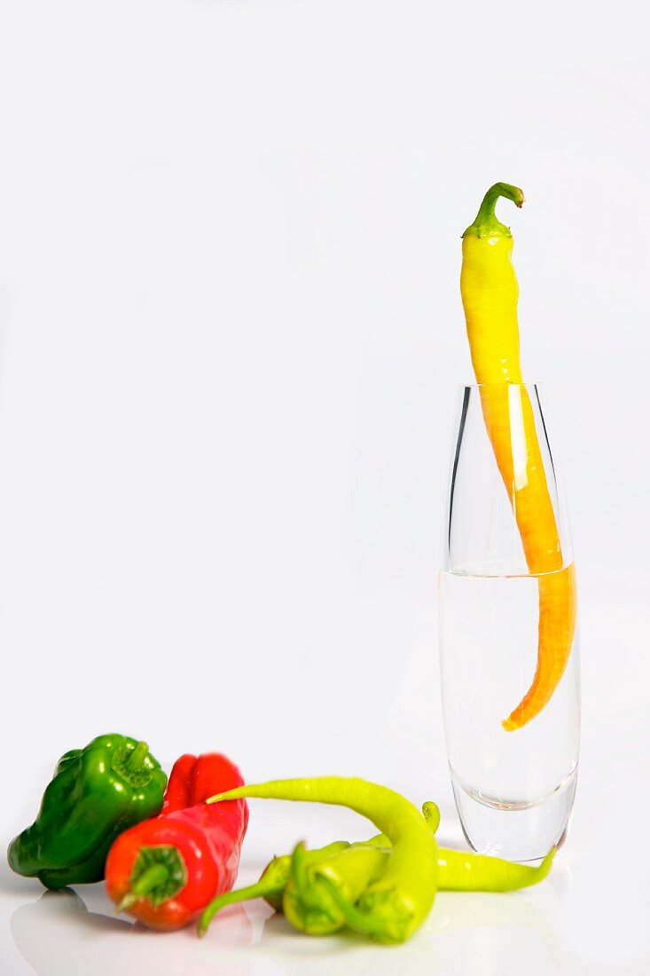 Assorted peppers, one in a glass vase