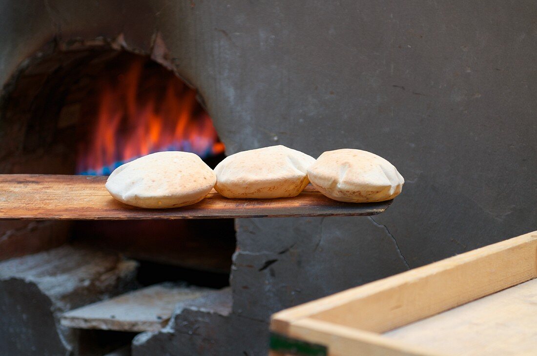 Libanesische Brote auf Holzschaufel vor Holzofen