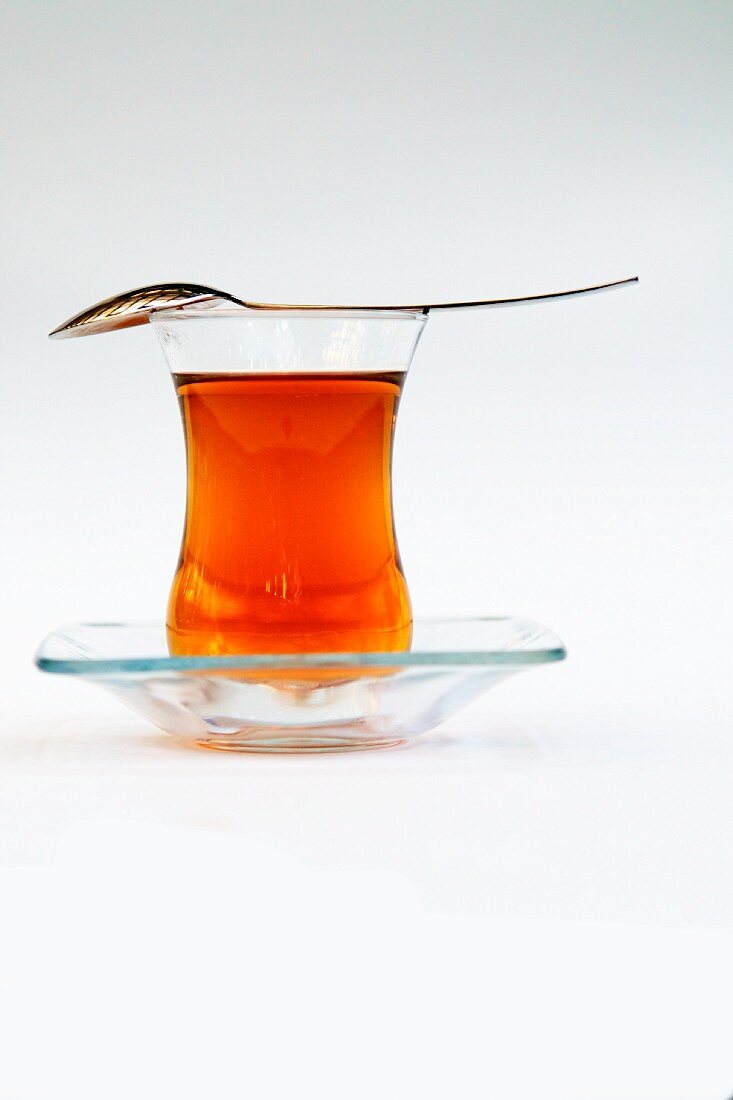 Orientalischer Tee in Teeglas mit darüberliegendem Löffel