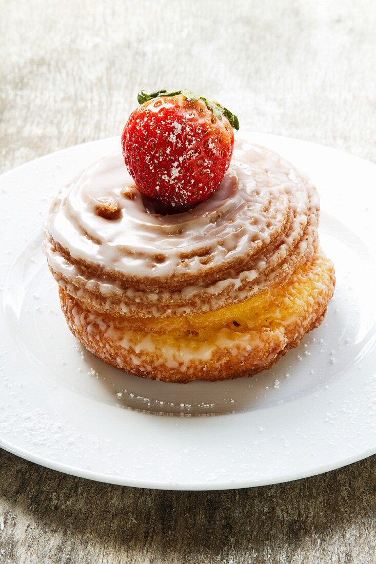 Yeast-raised pastry whirl with sugar glaze and a strawberry
