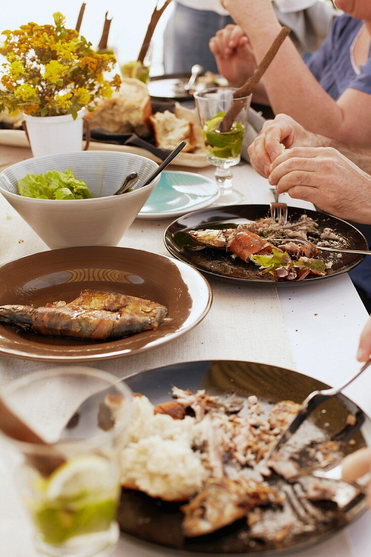 Gedeckter Tisch mit Grillfisch, Salat und Brot