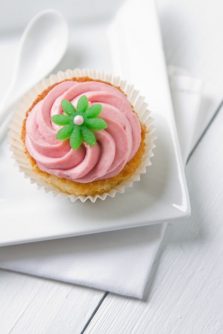 Cupcake mit pinkfarbener Creme und grüner Blüte